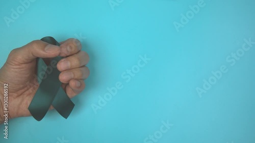 Footage video 4k. Hands holding teal ribbon on blue background.. Ovarian Cancer Awareness, Gynecological, Uterine Cancer, Vulvar Cancer, Panic Disorder, Post Traumatic Stress Disorder (PTSD).
