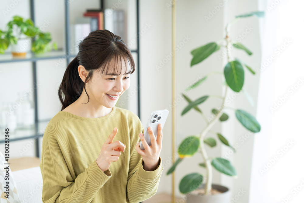 リビングでスマホを使う若い女性