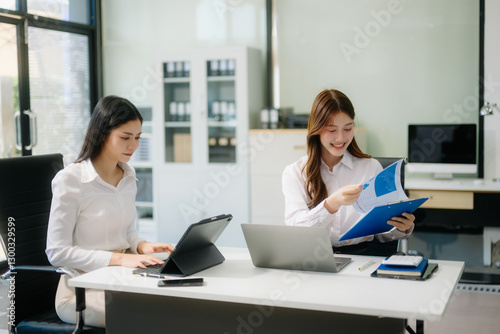 Businesswoman leading team meeting and using tablet and laptop computer with financial