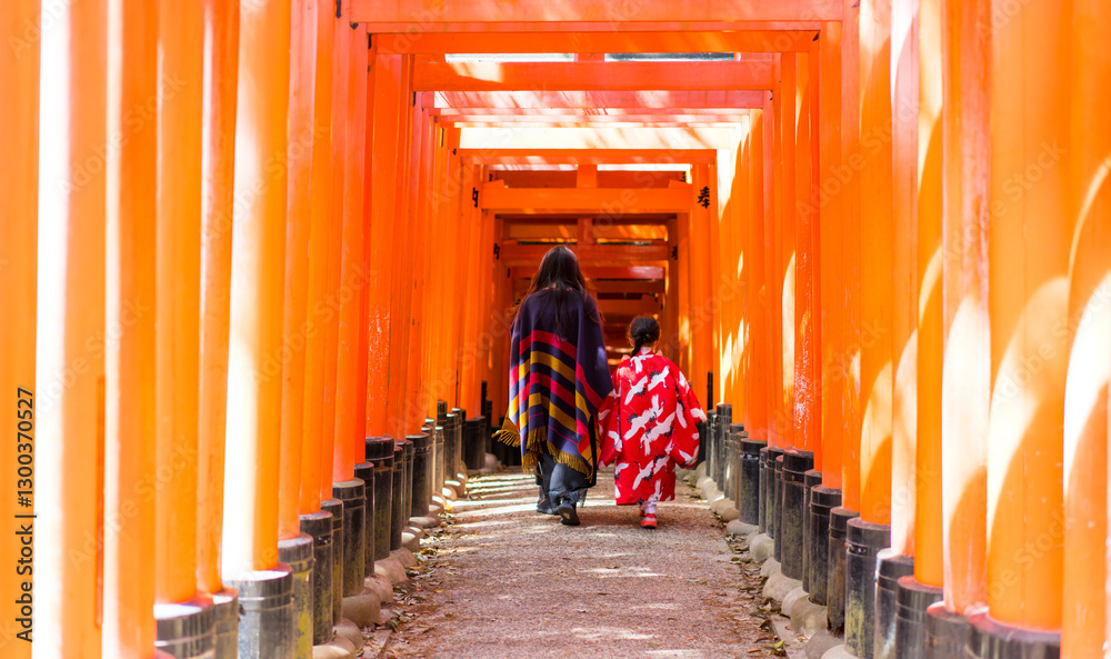 Mom and daughter walking under red gate in Kyoto Mom and daughter walking under red gate in Kyoto