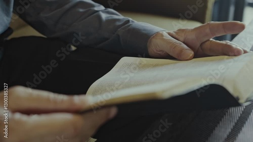 close up of hands of white businessman Reading the Bible in a Dimly Lit Living Room