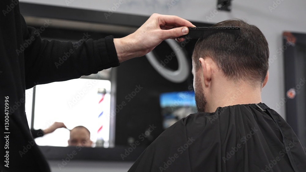 Fototapeta premium Professional hairdresser styling male client's hair, mirror reflecting classic barber pole, salon interior with modern grooming ambiance
