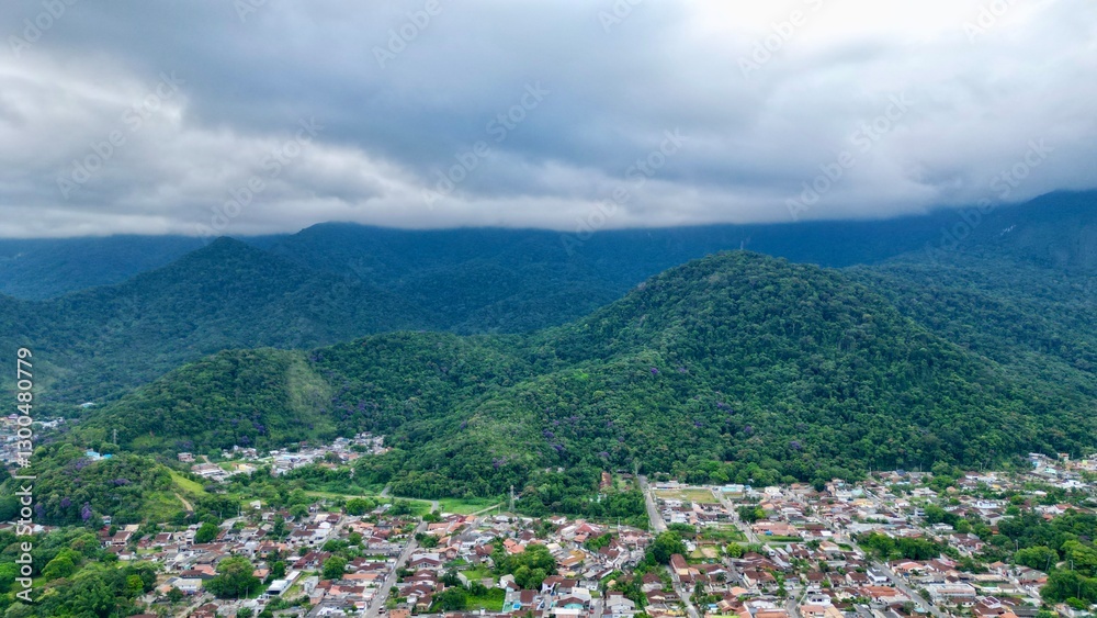 Fototapeta premium Linda vista aerea com drone sobre o mar com montanhas e cidade ao fundo com cores vibrantes.