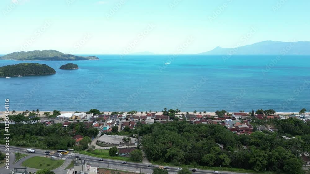Linda vista aerea com drone sobre o mar com montanhas e cidade ao fundo com cores vibrantes.