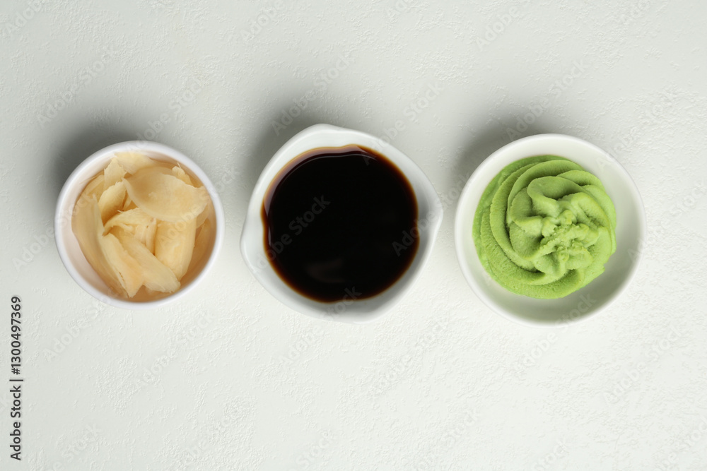 Fototapeta premium Hot wasabi paste, soy sauce and ginger on light textured table, flat lay