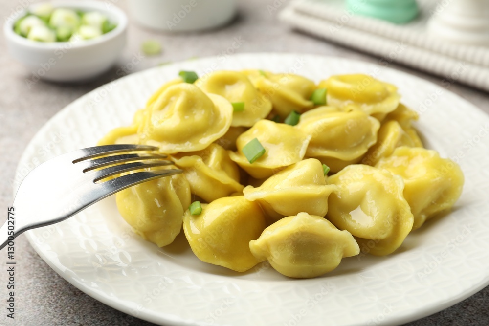 Tasty dumplings with green onion and fork on grey textured table, closeup Tasty dumplings with green onion and fork on grey textured table, closeup