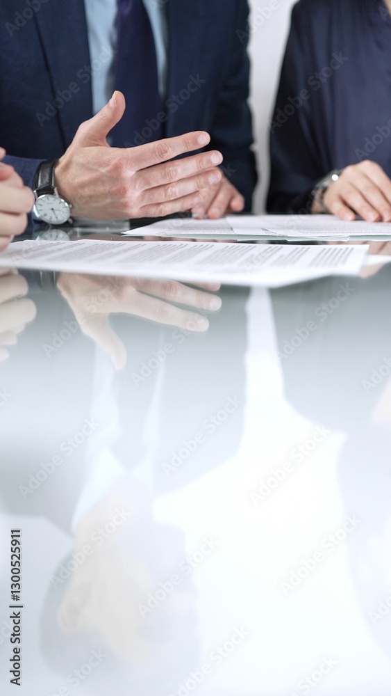 Business people are discussing a contract during meeting while sitting at the glass table in office, vertical close up view. Concept of success and team work