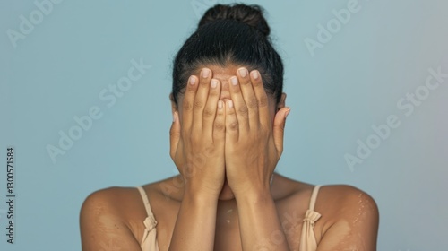A woman with hands covering her face.