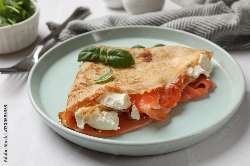 Delicious crepe with salmon, cream cheese and basil on white table, closeup Delicious crepe with salmon, cream cheese and basil on white table, closeup