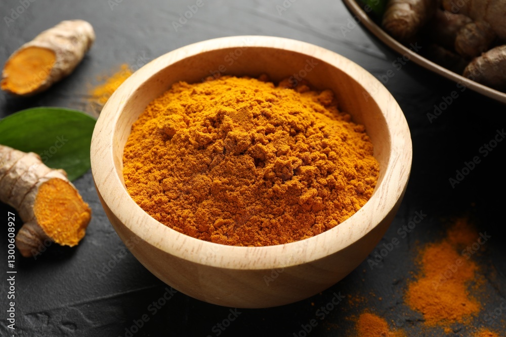 Aromatic turmeric powder in bowl and fresh roots on black table, closeup Aromatic turmeric powder in bowl and fresh roots on black table, closeup