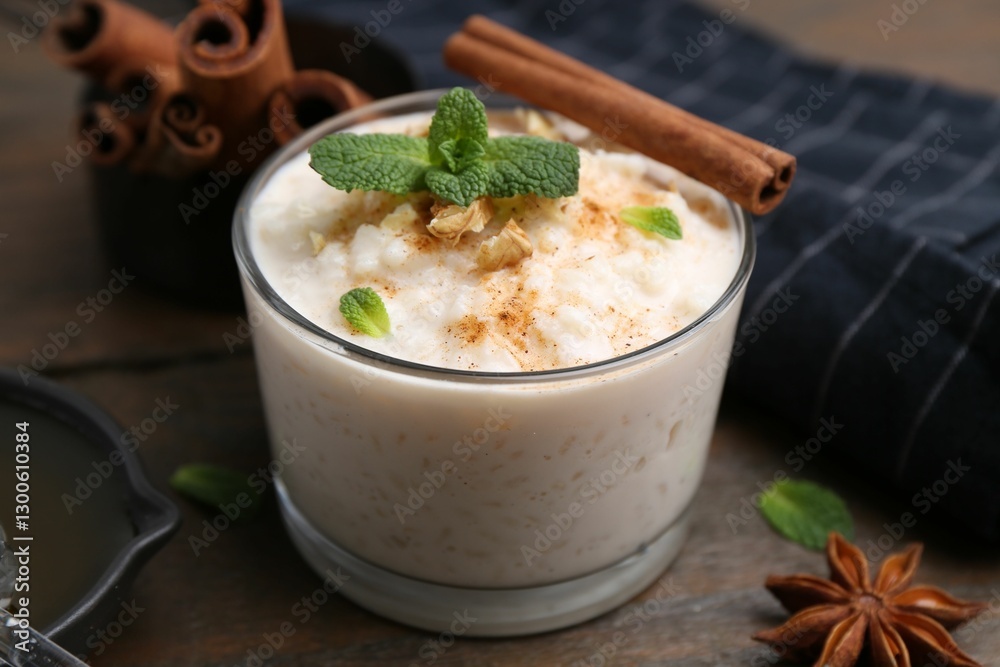 Tasty rice pudding with cinnamon, mint and nuts on wooden table, closeup Tasty rice pudding with cinnamon, mint and nuts on wooden table, closeup