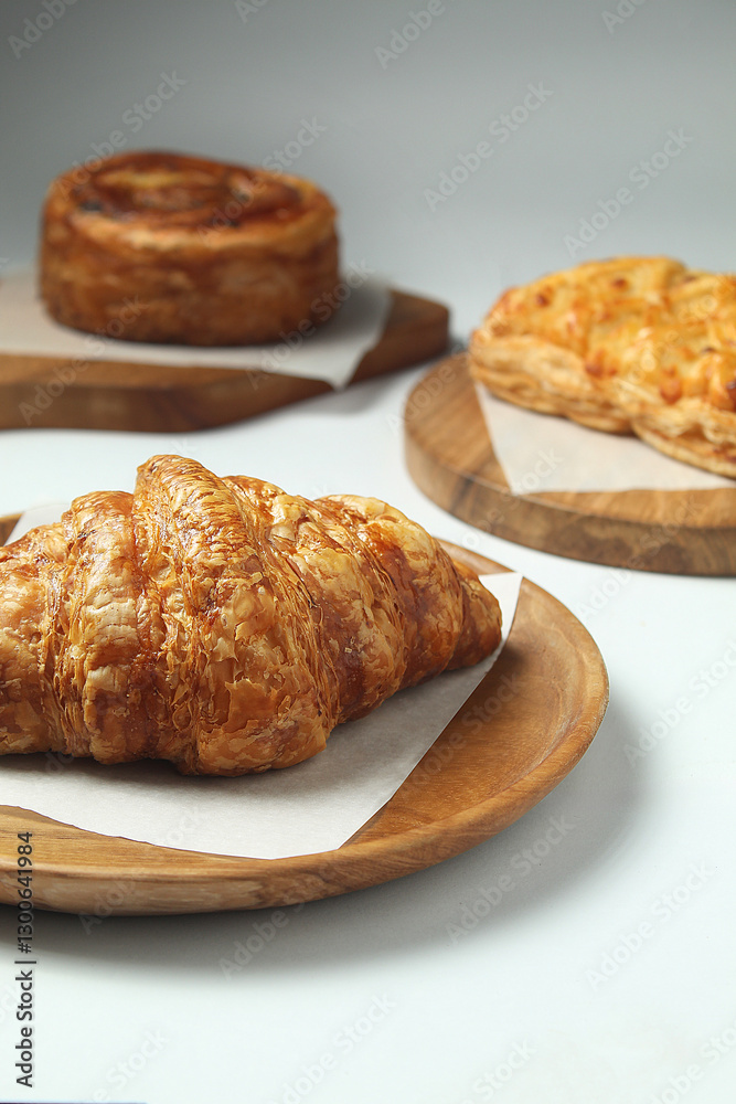 set of three french pastries, on top of a wooden cutting board, on white isolated background set of three french pastries, on top of a wooden cutting board, on white isolated background