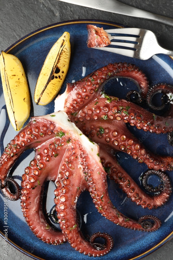 Obraz premium Fried octopus with herb sauce, lemon and cutlery on grey textured table, flat lay