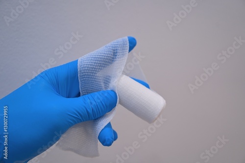 Medical Gloved Hand Holding Sterile Gauze and Bandage Roll