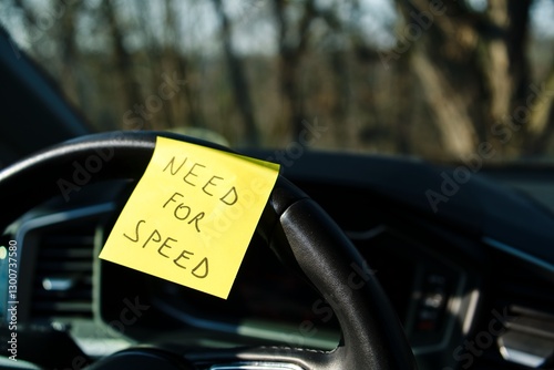 Sticky note with 'Need for Speed' on car steering wheel photo