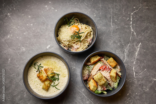 Obraz na płótnie Gourmet pasta, salad, and creamy soup in bowls on marble surface, showcasing elegant dining dish concept w salonie
