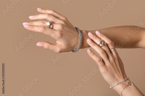 Female hands with silver rings and bracelets on beige background, closeup