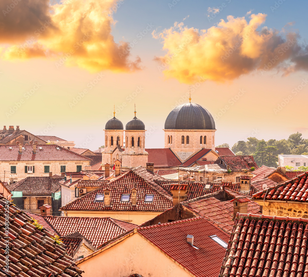 Fototapeta premium beautiful old city sunset landscape with ren and orange tile roofs of houses and nice cathedral church in traditional venetian style with bell tower and chapel and evening sky on background