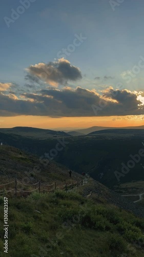 Landscape view during sunset atop a mountain ridge with clouds and valleys in the distance