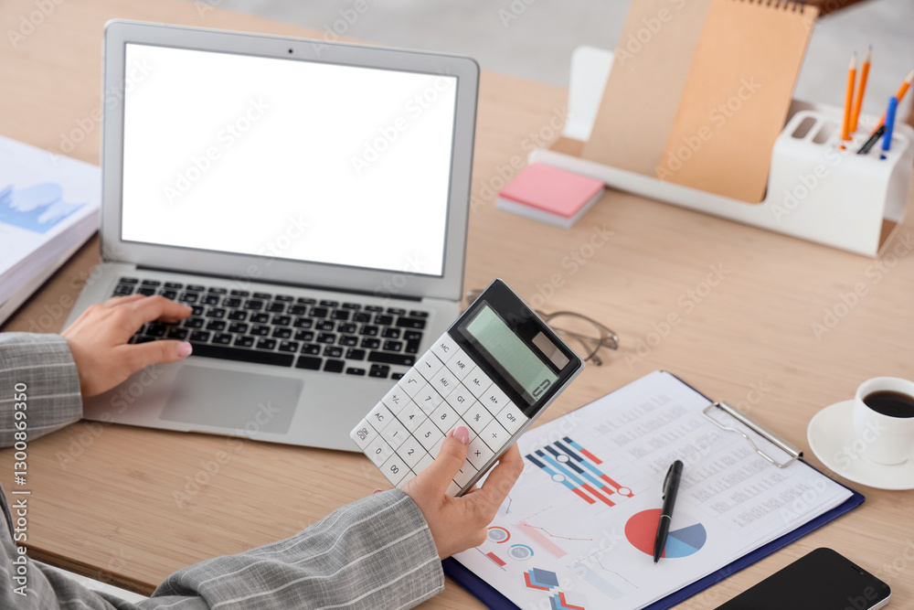 Young businesswoman with laptop and calculator working on report at table in office, closeup Young businesswoman with laptop and calculator working on report at table in office, closeup