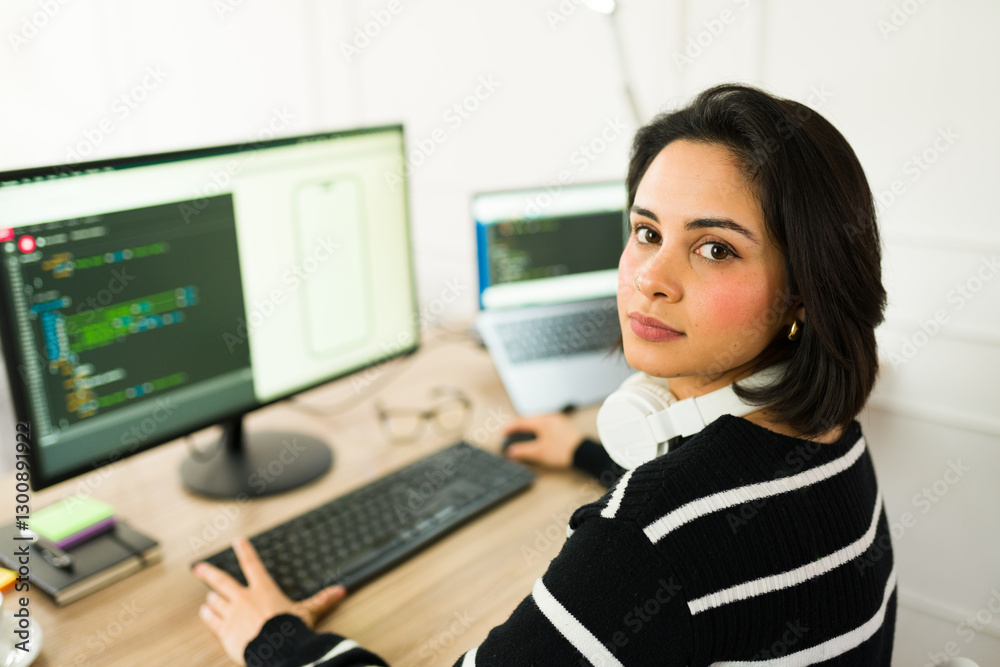 Latin software developer working from home coding an app using desktop computer and laptop Latin software developer working from home coding an app using desktop computer and laptop
