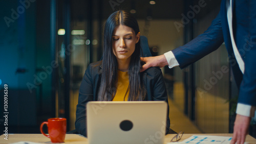 Quadro su tela Businesswoman in a black blazer and yellow blouse sits at a desk with a laptop, looking uncomfortable as a man in a suit places his hand on her shoulder