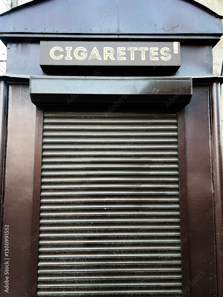 Obraz premium Closed rolling shutter kiosk with cigarettes sign on top viewed closely.