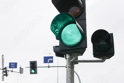Green traffic light at an intersection on a cloudy day. Road safety and transportation control signal. Urban street scene guiding vehicles and pedestrians.