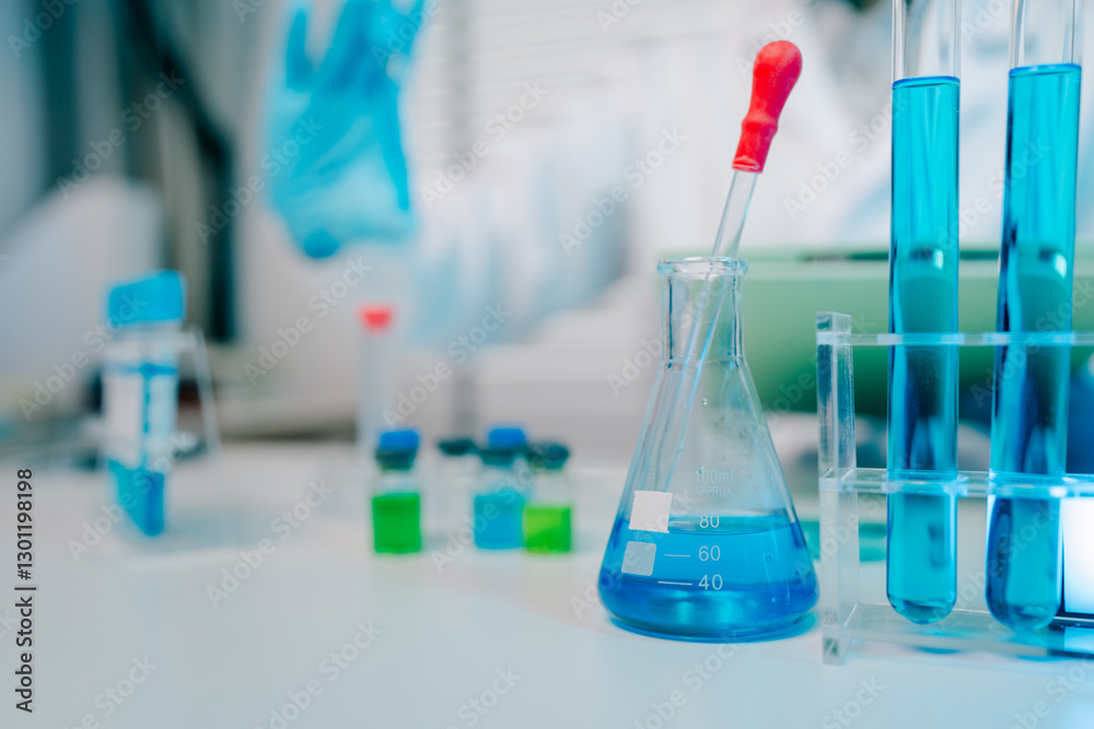 Lab table with a blue beaker and a red dropper Lab table with a blue beaker and a red dropper