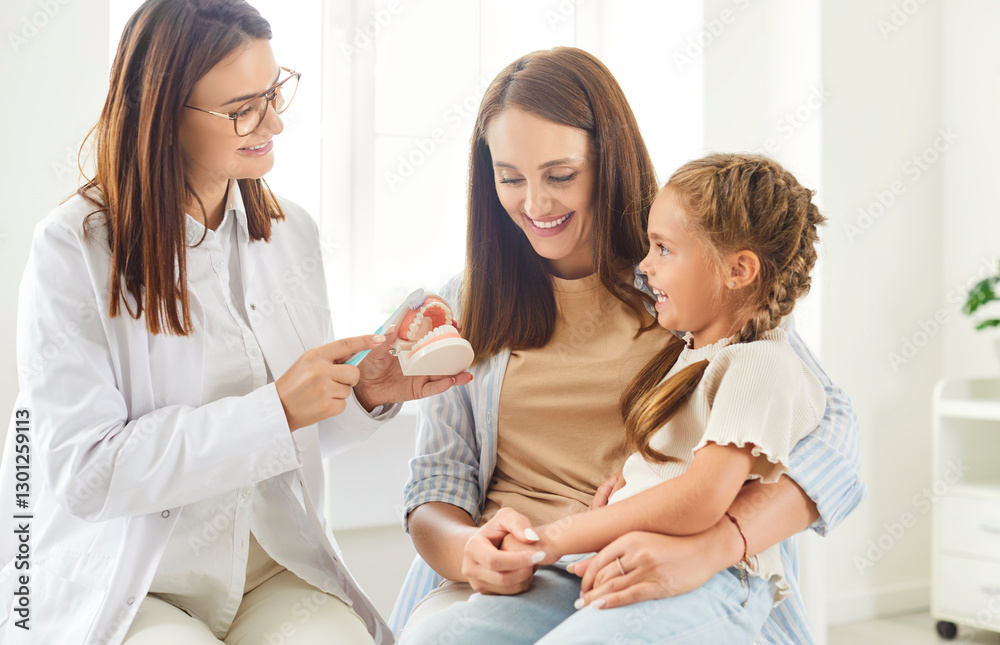 Mother and girl attend an appointment with a dentist doctor or nurse to learn about tooth cleaning. Dental care session, teaching how to use toothbrush and oral hygiene to the child in the clinic. Mother and girl attend an appointment with a dentist doctor or nurse to learn about tooth cleaning. Dental care session, teaching how to use toothbrush and oral hygiene to the child in the clinic.