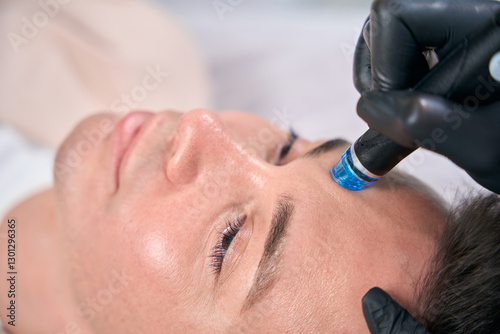 Close-up view man visiting cosmetologist, doing hydrafacial procedure