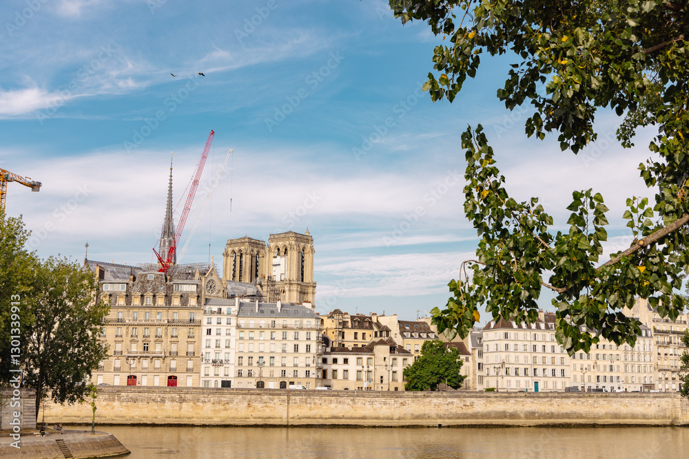 View of seine river in paris with notre dame church under construction just over the river with visible cranes