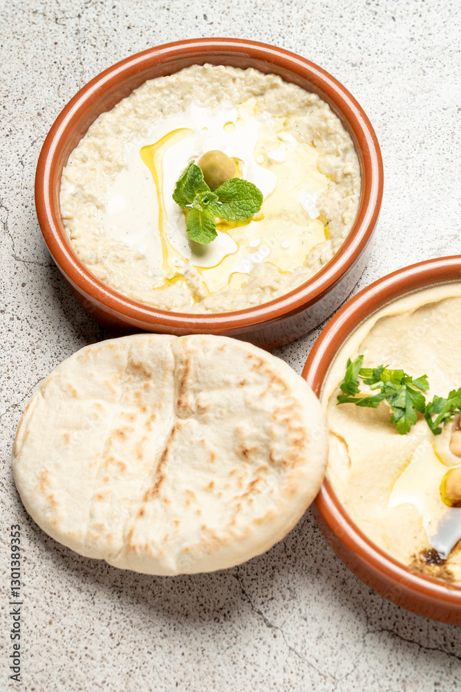 Hummus and baba ghanoush with pita bread and olive oil on gray background Hummus and baba ghanoush with pita bread and olive oil on gray background