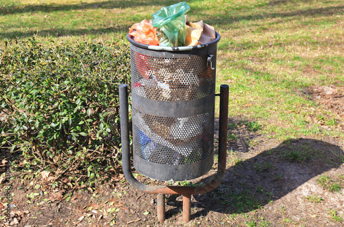 Metal trash bin. Small barrel-shaped trash can for small trash. Garbage equipment for sidewalks and yard areas. Garbage can for small waste.  Environmental situation and garbage in a big city. Waste