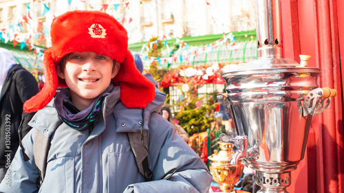  Teenage boy in a Russian red ushanka hat with the USSR coat of arms on the hat. At the traditional holiday 