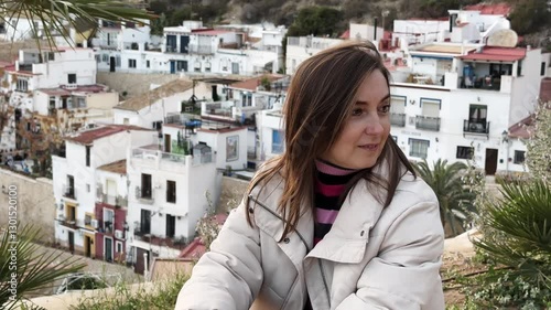 Scenic old town cityscape, female tourist sitting on viewpoint and contemplating picturesque urban landscape with serene mediterranean atmosphere. A pigeon flies by