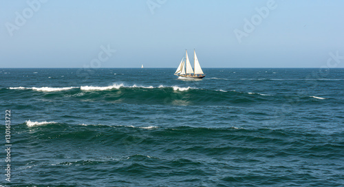 Sailboat on the Ocean with Blue Sky and Waves in a Scenic Summer Seascape