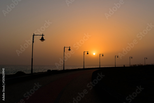 Street light silhouettes in a row at playa honda beach promenade at sunset, lanzarote, canary islands., spain. travel europe.