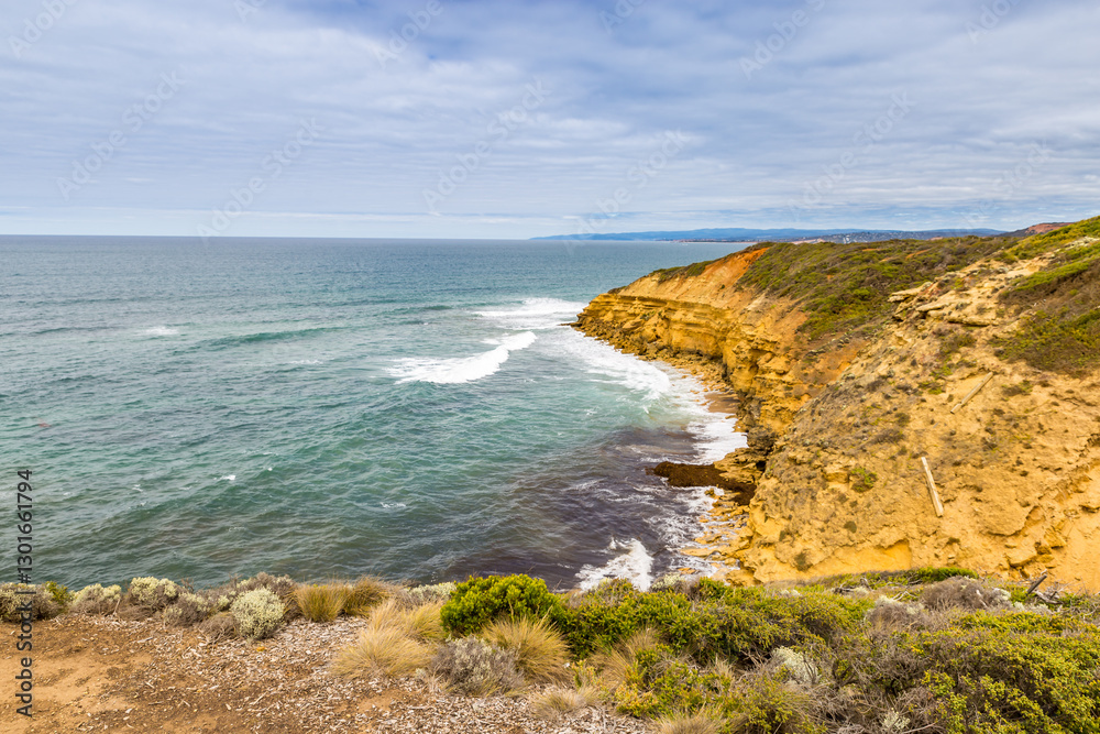 Rugged cliffs rise above tranquil waves, revealing a secluded beach in Port Campbell National Park at the Great Ocean Road. Rugged cliffs rise above tranquil waves, revealing a secluded beach in Port Campbell National Park at the Great Ocean Road.
