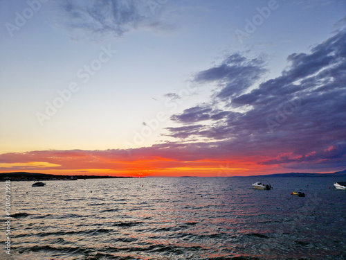 Vibrant sunset over the sea with boats and colorful clouds