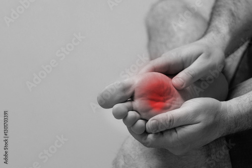 A man experiences pain after long walks, sports, wearing uncomfortable shoes or insufficient foot care. black and white photo red foot