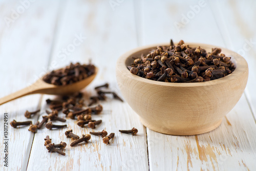 Fototapeta Naklejka Na Ścianę i Meble -  cloves spice in a wooden bowl on a light kitchen table,  selective focus.