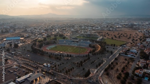 Aerial view of a sports stadium surrounded by a suburban landscape at sunset.