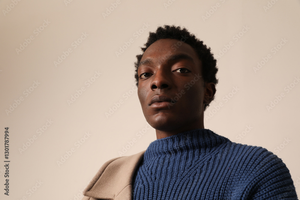 Headshot of young African American man wearing blue sweater posing over light background. Headshot of young African American man wearing blue sweater posing over light background.