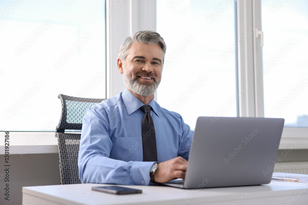 Banker working on laptop at desk in office Banker working on laptop at desk in office