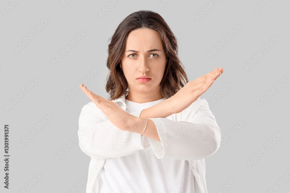 Young woman showing STOP gesture on light background. Rules concept Young woman showing STOP gesture on light background. Rules concept