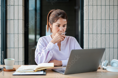 Woman concentrating on laptop work at home office desk with coffee and notebook, showcasing productivity and modern lifestyle. photo