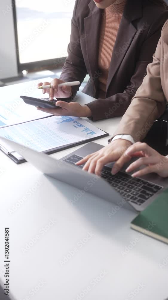 Close-up of two businesswomen working at desk discussing business strategies, analyzing financial charts, planning marketing plans and using laptop to drive business growth in professional office Close-up of two businesswomen working at desk discussing business strategies, analyzing financial charts, planning marketing plans and using laptop to drive business growth in professional office