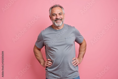 Cheerful Middle-aged Man with Gray Hair Smiling in a Casual Gray T-shirt Against a Pink Background, Radiating Confidence and Positivity