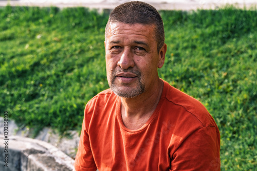 Colombian Latino male senior adult, looking at camera outside in a park